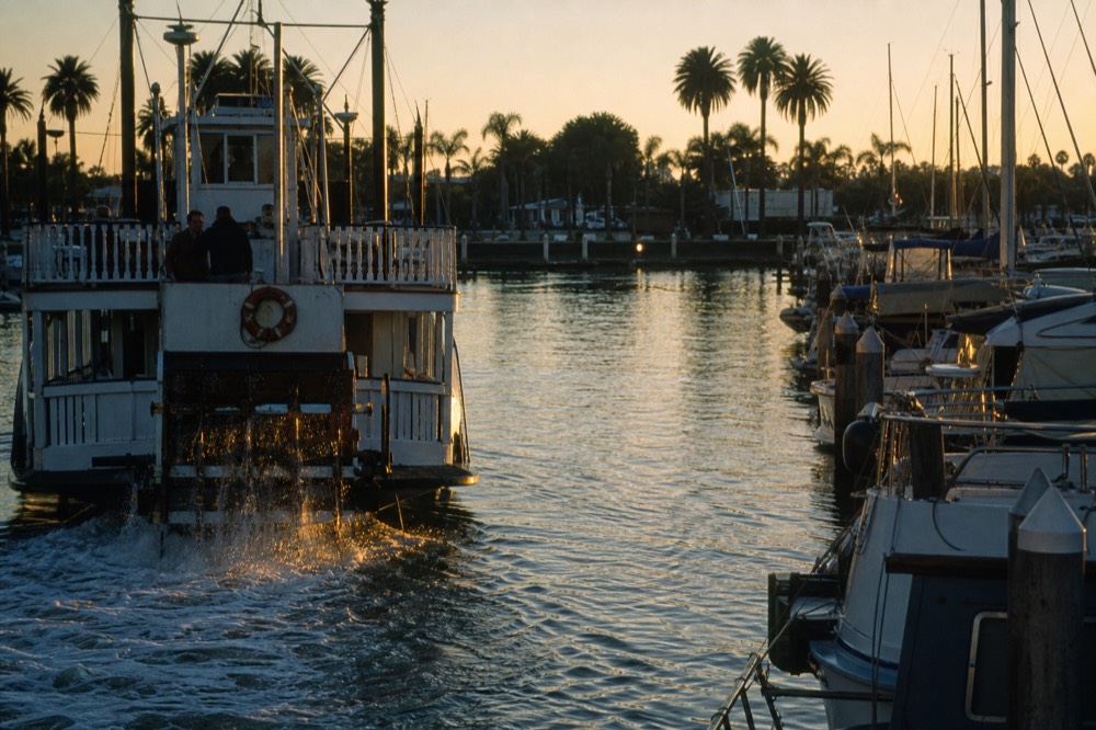 Paddlewheel riverboat cruising a Fort Lauderdale waterway at sunset past docked boats, no text, no logos, no people