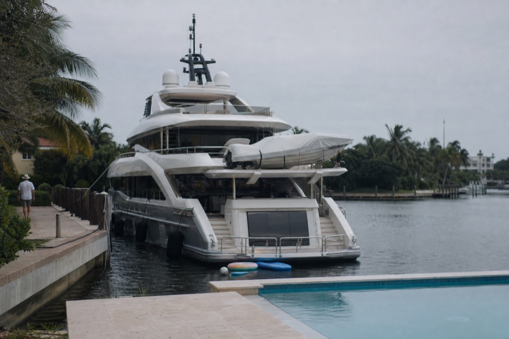 Mega-yacht moored at a private dock behind a waterfront home on the Intracoastal, no text, no logos, no people