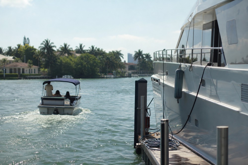 A small dinner cruise boat passing mega-yachts on the Fort Lauderdale Intracoastal, no text, no logos, no people
