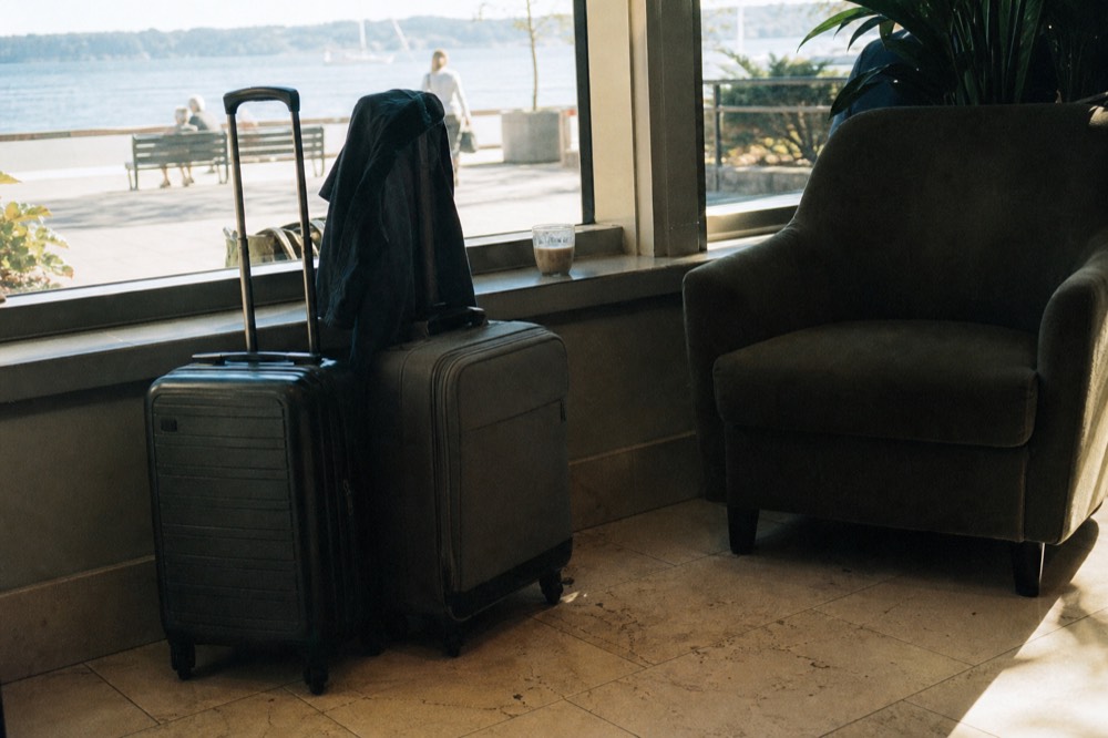 Rolling suitcases waiting in a hotel lobby near a waterfront window, no text, no logos, no people