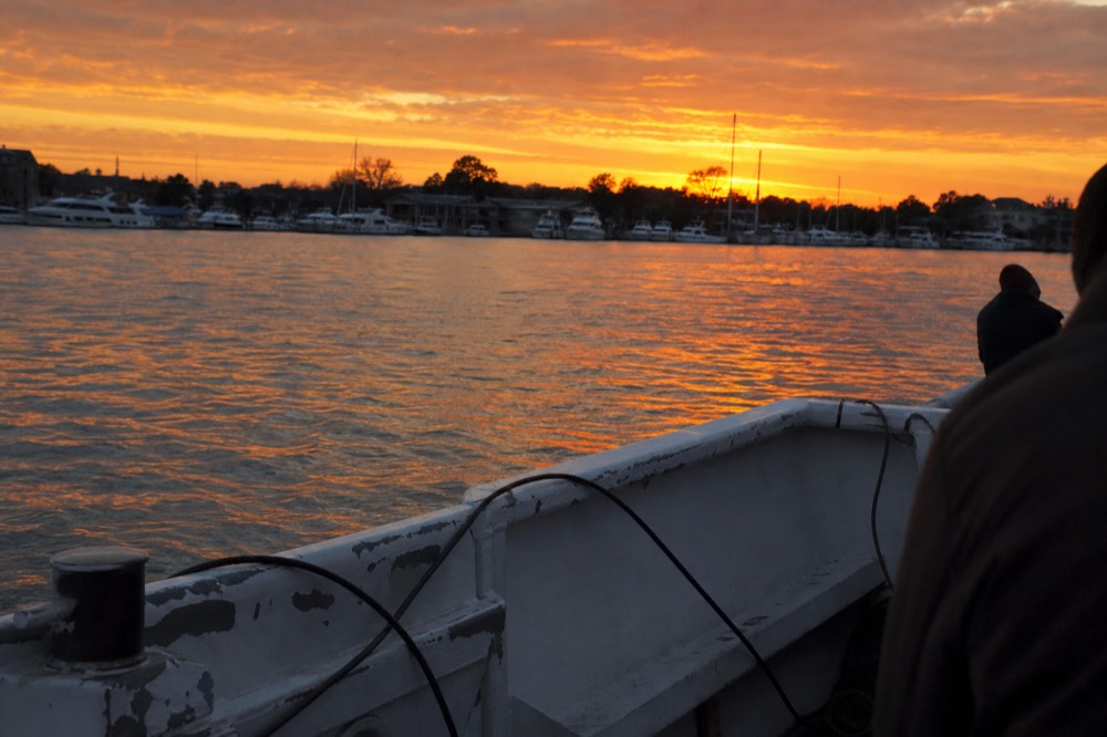A boat cruising the Intracoastal Waterway under a vivid orange sunset sky, no text, no logos, no people