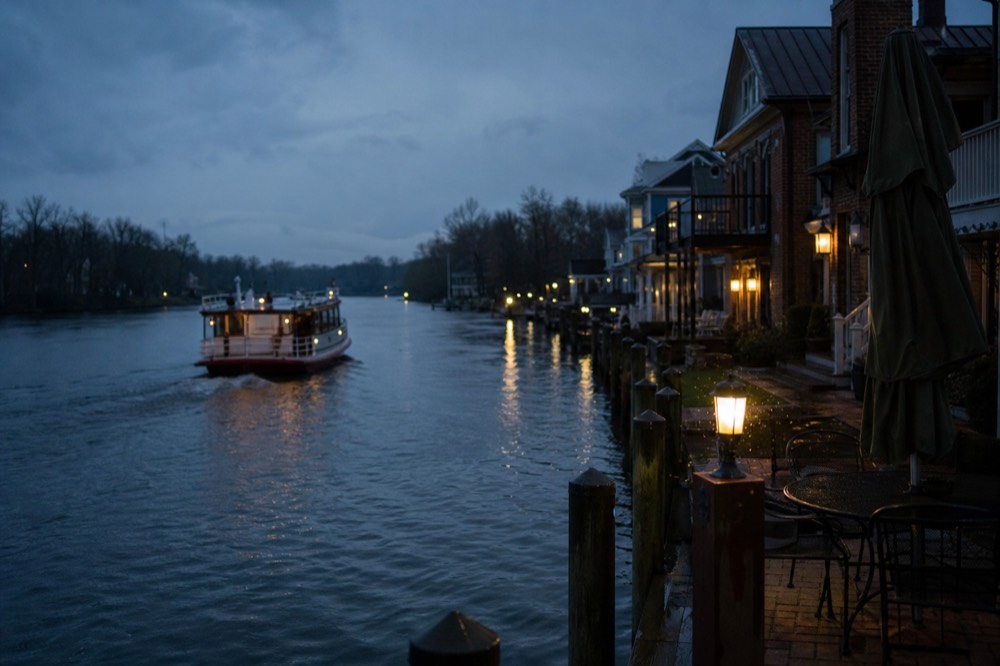 Riverboat cruising the New River past waterfront homes at dusk, no text, no logos, no people.