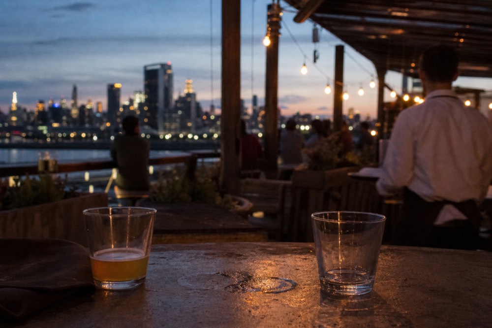 Rooftop bar overlooking the city skyline at dusk, no text, no logos, no people.